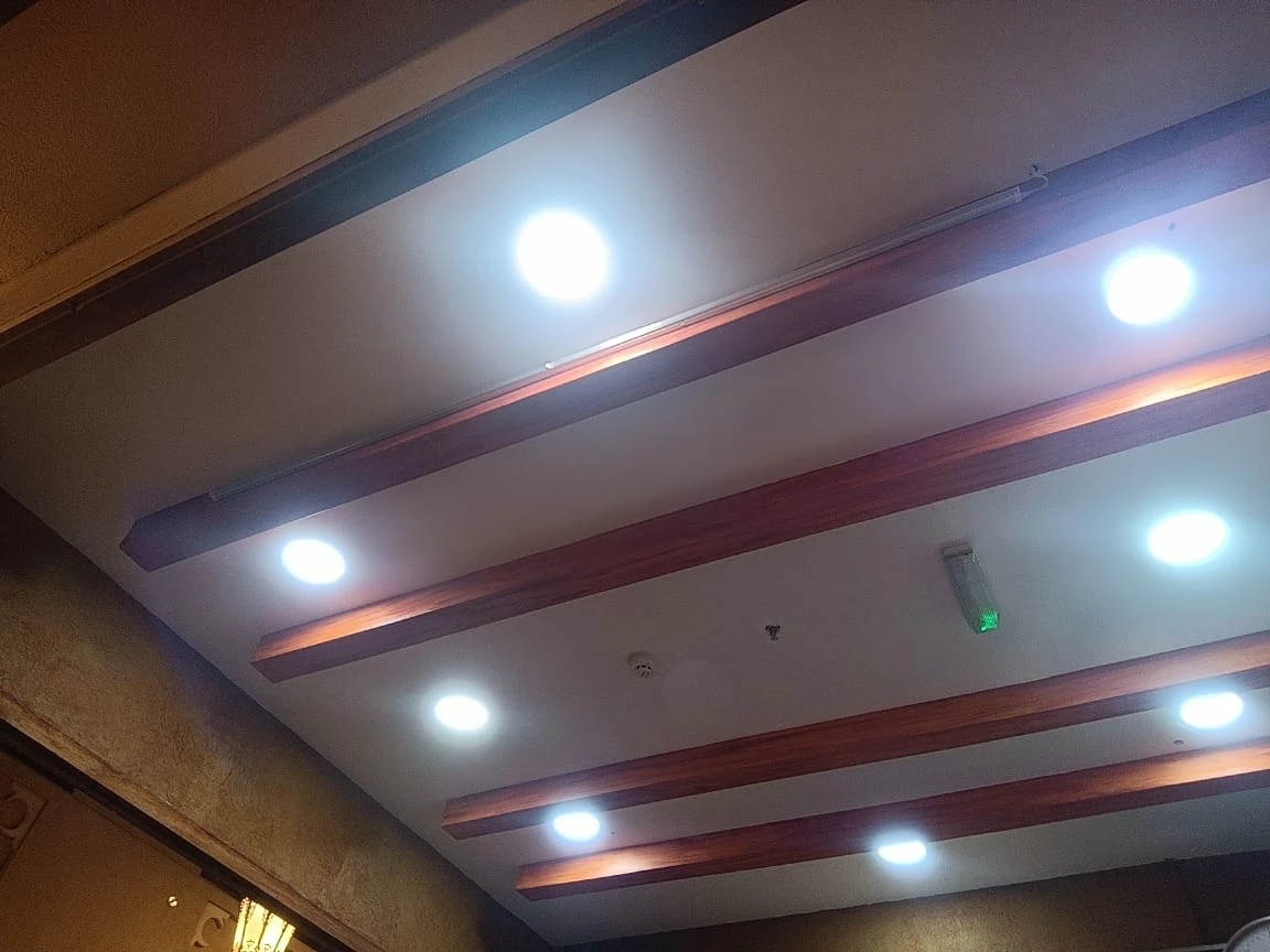 سقف أبيض بجسور بتأثير خشبي وإنارة LED دائرية