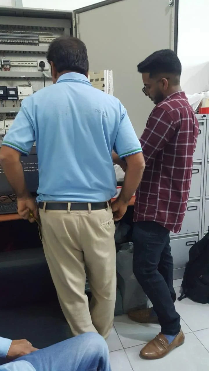فنيون يفحصون لوحة تحكم كهربائية مفتوحة في الموقع